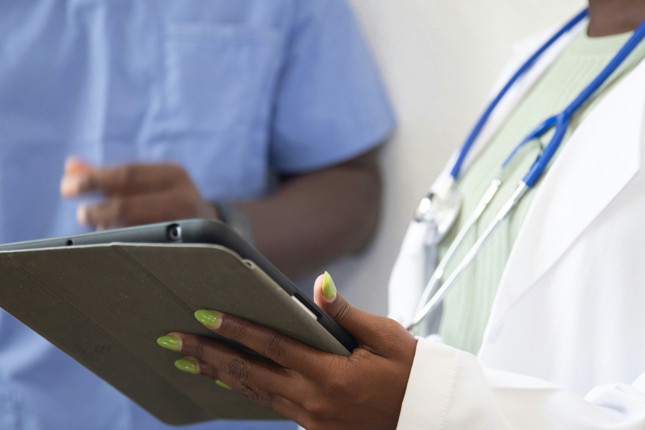 Doctor with a stethoscope reviewing patient information on a tablet with a nurse