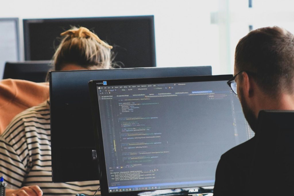 Ontwikkelaars werken aan code op grote schermen