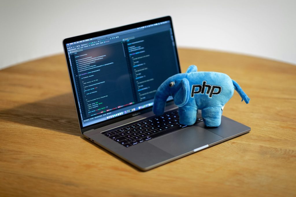Blauwe PHP-olifant naast een laptop met code op het scherm